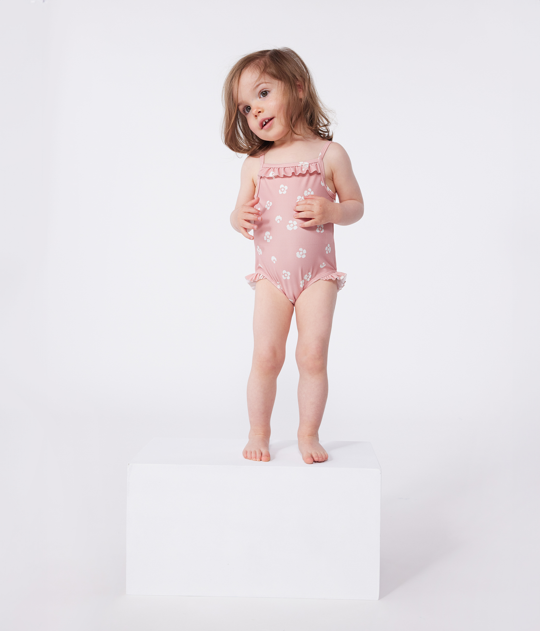 Babies' one-piece swimsuit with frills and a floral print.
