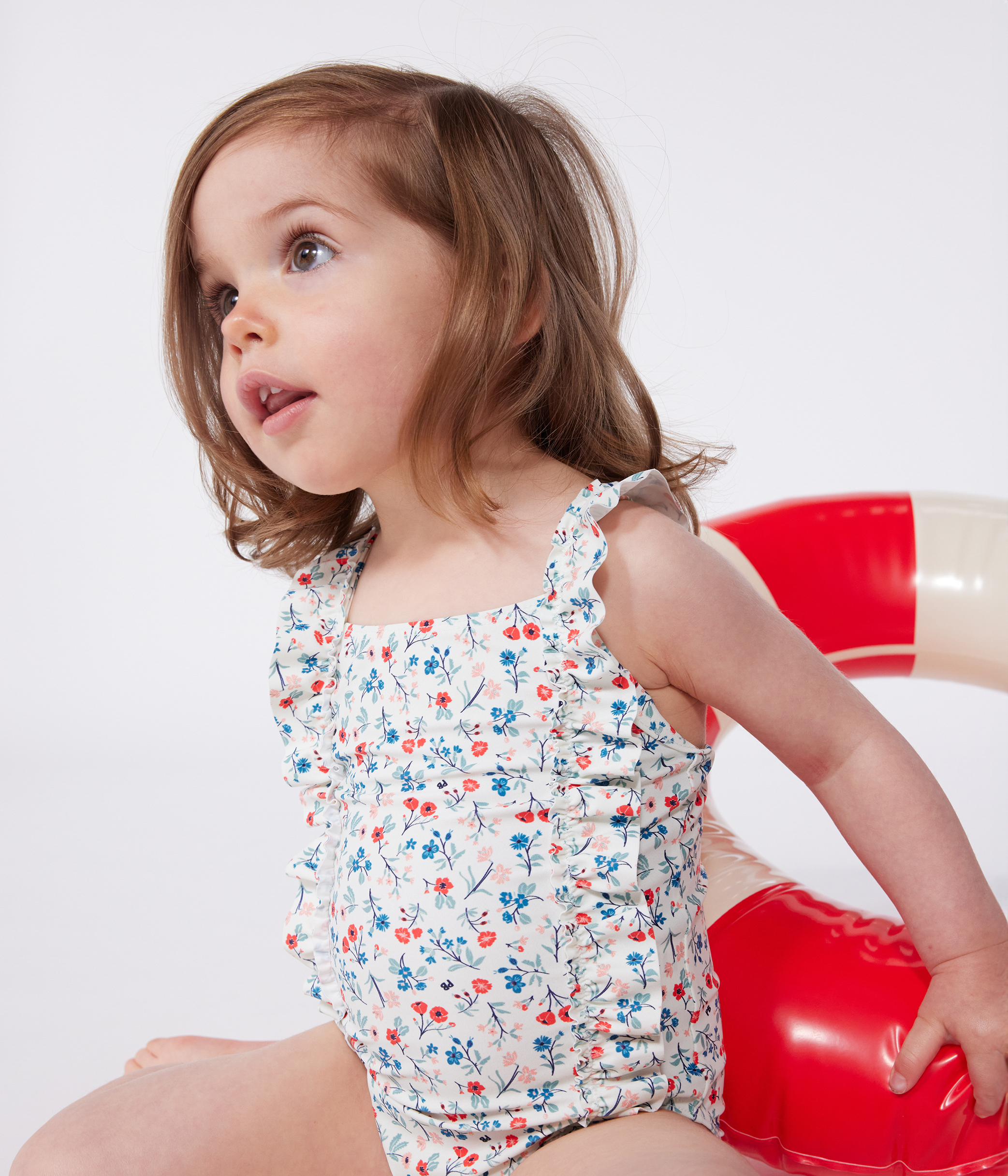 Babies' one-piece swimsuit with frills and a floral print.